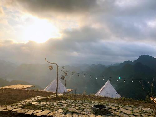 two white tents on top of a hill with the sun at Sunrise Ha Giang Camping An Introspective Stay in Suy Tung Su