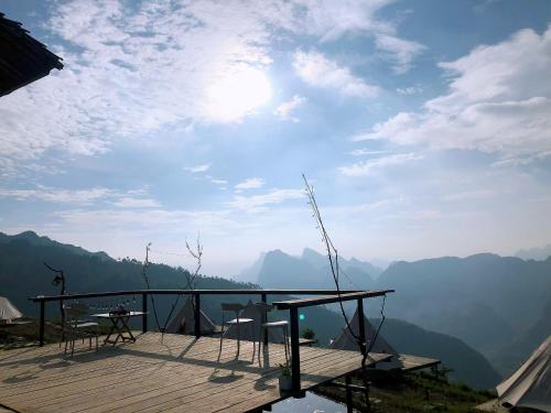 a wooden deck with a table and chairs on top of a mountain at Sunrise Ha Giang Camping An Introspective Stay in Suy Tung Su