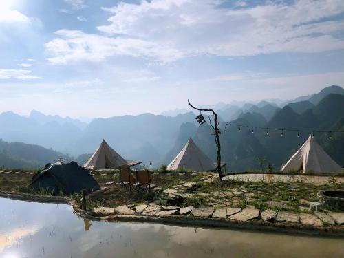 a group of tents with mountains in the background at Sunrise Ha Giang Camping An Introspective Stay in Suy Tung Su