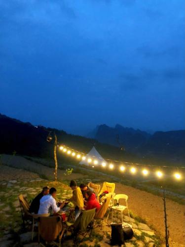 a group of people sitting at a table on the beach at night at Sunrise Ha Giang Camping An Introspective Stay in Suy Tung Su