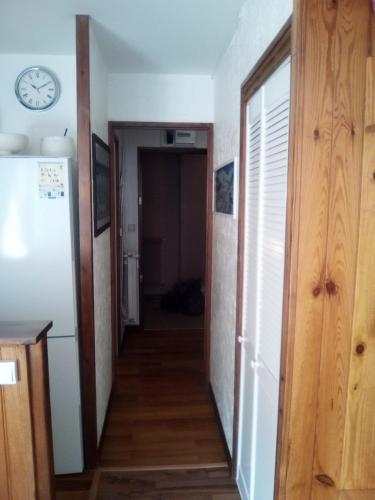 un couloir menant à une pièce avec une horloge au mur dans l'établissement Joli studio aux pieds des pistes, à Allos