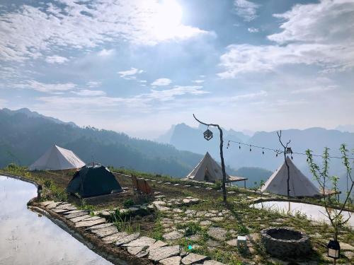 a group of tents next to a body of water at Sunrise Ha Giang Camping An Introspective Stay in Suy Tung Su