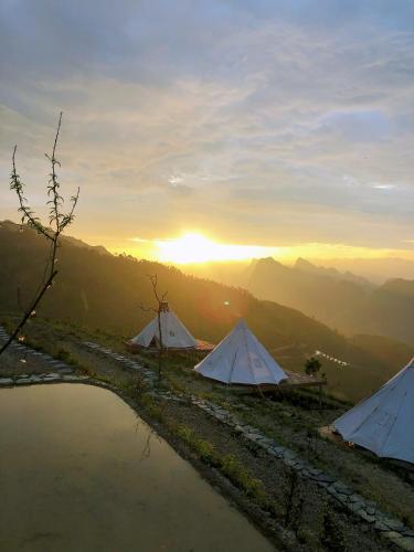 two tents on a hill with the sunset in the background at Sunrise Ha Giang Camping An Introspective Stay in Suy Tung Su