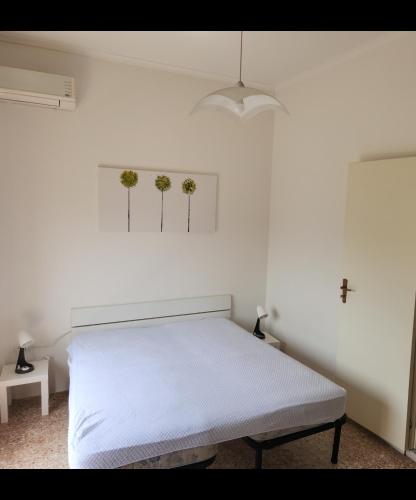 a bedroom with a white bed and two plants on the wall at Zia Memè in Taviano