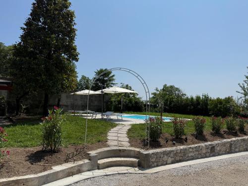 a garden with a swimming pool and umbrellas at All'Antica Scuderia Del Castello in Maiano