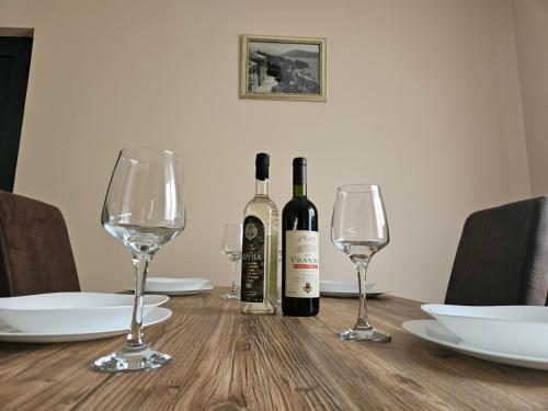 a table with two bottles of wine and two glasses at Apartman Palma in Kumbor