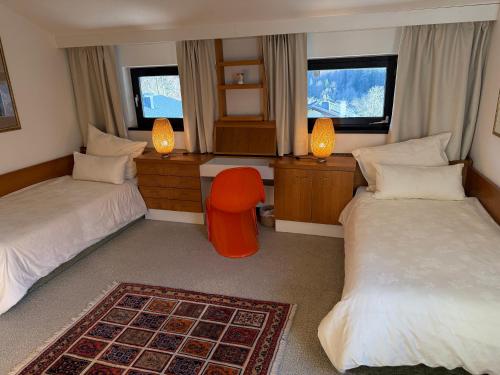 a bedroom with two beds and a orange chair in it at Die Landhausvilla in Unterach am Attersee in Unterach am Attersee