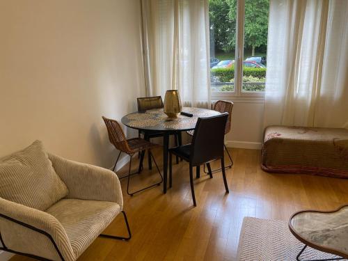 un salon avec une table et des chaises et une fenêtre dans l'établissement Serene Stay in Eiffel Park, à Sèvres