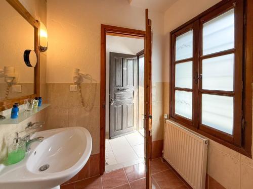 a bathroom with a sink and a window and a mirror at Pliades Traditional Guesthouse in Palaios Panteleimon