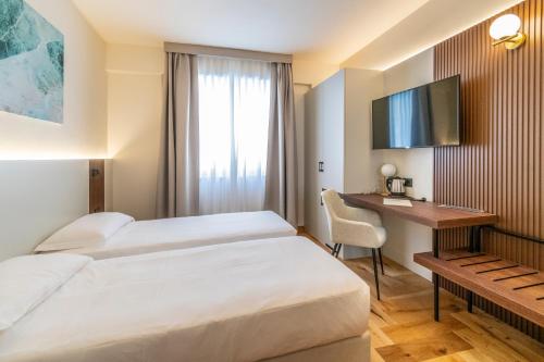 a hotel room with two beds and a desk at Madi city Hotel in LʼAquila