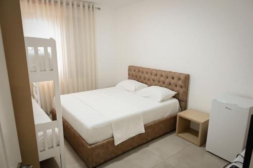 a small bedroom with a bed with white sheets at Vila Venezia in Shëngjin