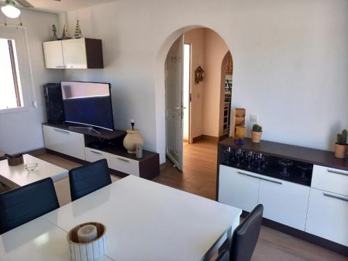 Una cocina y un comedor con una mesa y sillas blancas. en Can Xubec, en Cala'n Bosch