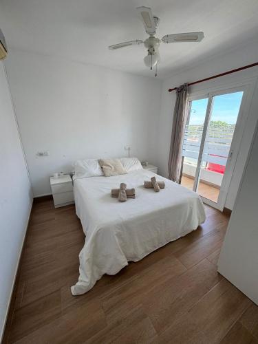 a bedroom with a white bed with two towels on it at Can Xubec in Cala en Bosc