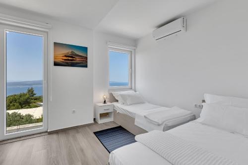 a white room with two beds and a window at Villa la Perla in Baška Voda