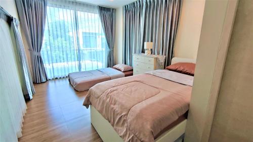 a bedroom with two beds and a large window at Family House Casa Seaside Rayong in Ban Chak Phai