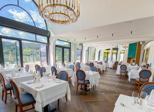 una sala da pranzo con tavoli, sedie e lampadario a braccio di Hotel See-Villa a Millstatt