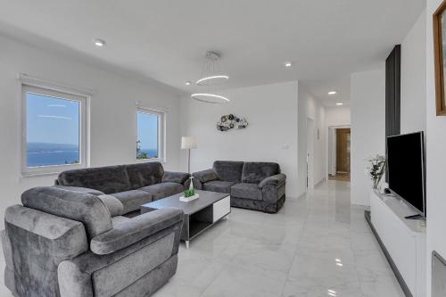 a living room with two couches and a tv at Villa la Perla in Baška Voda