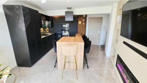 une cuisine avec une table en bois et des armoires noires dans l'établissement L'Eden Palavas Sublime T3 de 70m 2 -Terrasse Parking - 2 pas de la plage, à Palavas-les-Flots