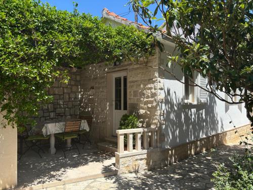 a small white house with a table and chairs at Apartment Ivic in Bol