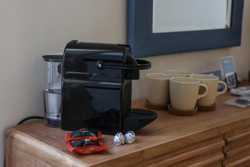 a black blender sitting on a wooden counter with cups at Alma Home Experience in Ventimiglia