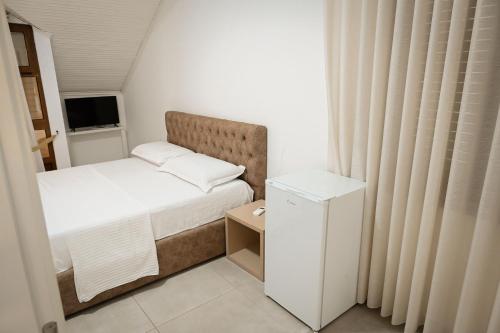 a small bedroom with a bed and a small refrigerator at Vila Venezia in Shëngjin