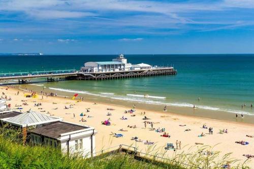 ein Strand mit einem Pier und Menschen auf dem Sand in der Unterkunft Double Room with share in Parkstone