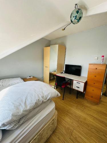 ein Schlafzimmer mit einem Bett und einem Schreibtisch mit einem Computer in der Unterkunft Double Room with share in Parkstone