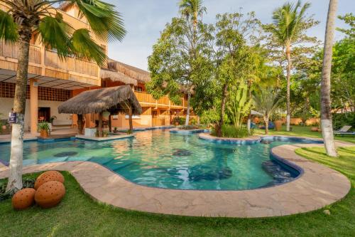 a swimming pool in front of a building with palm trees at Dayo Hotel in Flecheiras