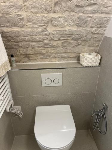 a bathroom with a white toilet and a stone wall at La Loggetta in Noci