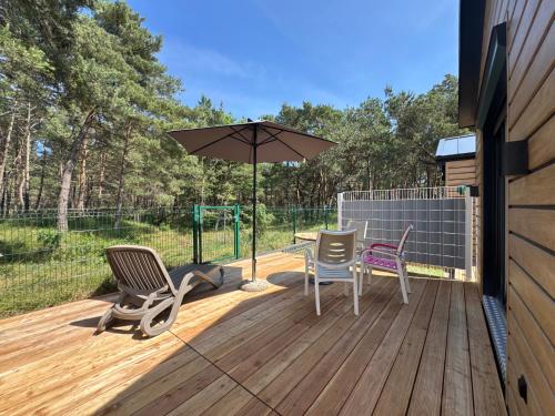 a patio with chairs and an umbrella on a deck at Apartamenty i Domki WyDmy Międzywodzie in Międzywodzie