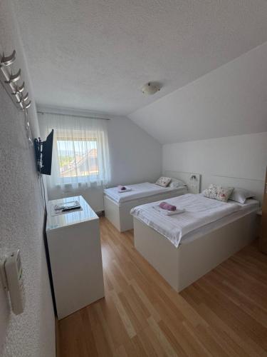 a room with two beds and a window at Sobe Matovinović in Lovinac