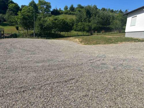 a gravel driveway with a white building and trees at Vila Fina in Laktaši