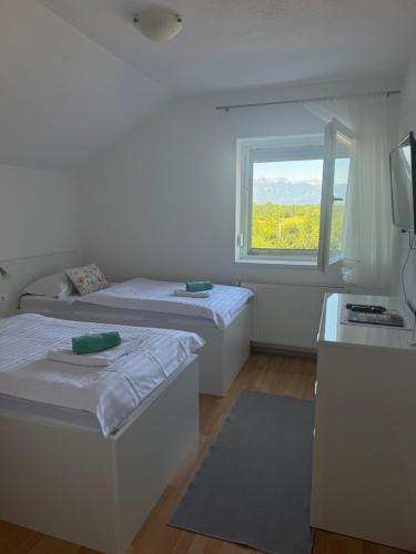 a white room with two beds and a window at Sobe Matovinović in Lovinac