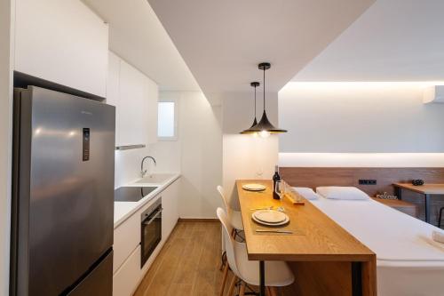 a kitchen with a wooden table and a stainless steel refrigerator at Anna's Lovely Corfu Studio in Corfu