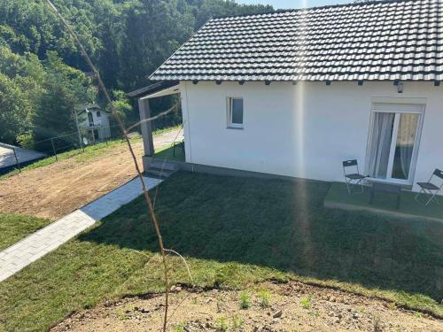a small white house with a yard with a tree at Vila Fina in Laktaši