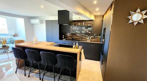 une cuisine avec un bar avec des armoires noires et une cuisinière dans l'établissement L'Eden Palavas Sublime T3 de 70m 2 -Terrasse Parking - 2 pas de la plage, à Palavas-les-Flots