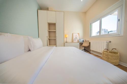 a large white bed in a room with a window at Face à la Baie, Vue Panoramique in LʼAgha