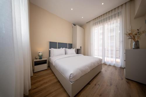 a bedroom with a white bed and a large window at Cross views city, sea in LʼAgha