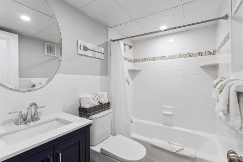 a white bathroom with a sink and a toilet and a mirror at 301 Ocean Ave, Unit 206 - The Harbor Light in North Wildwood