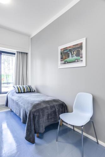 a bedroom with a bed and a white chair at Forenom Hostel Vantaa Aviapolis in Vantaa