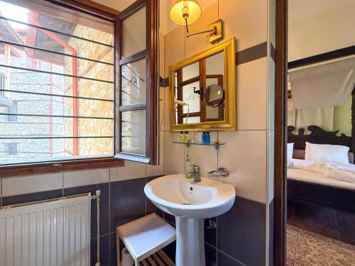 a bathroom with a sink and a mirror and a bed at Pliades Traditional Guesthouse in Palaios Panteleimon