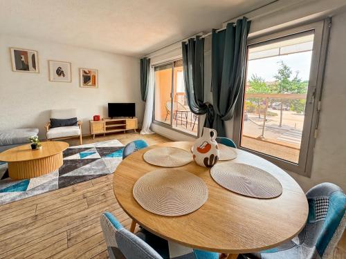 - un salon avec une table en bois et une grande fenêtre dans l'établissement L'escale Arcachonnaise, à Arcachon