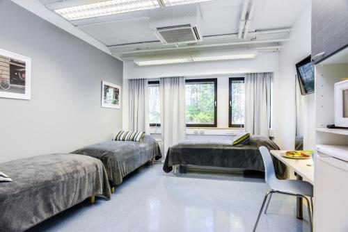 a bedroom with two beds and a desk and a table at Forenom Hostel Vantaa Aviapolis in Vantaa