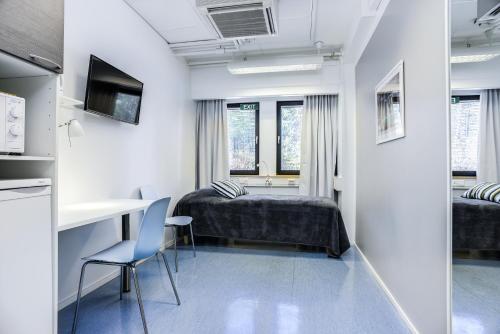 a room with a bed and a desk and a table at Forenom Hostel Vantaa Aviapolis in Vantaa
