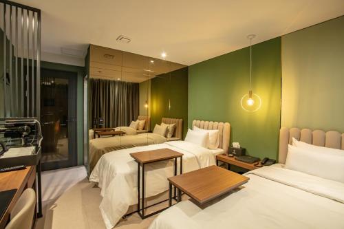 Habitación de hotel con 3 camas y paredes verdes en On the Moon Hotel, en Wonju