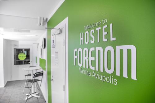 a green wall in a room with a table and chairs at Forenom Hostel Vantaa Aviapolis in Vantaa