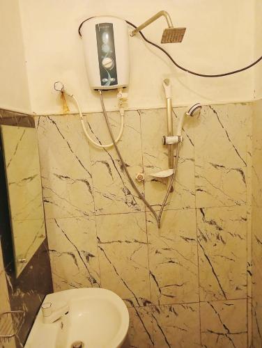 a bathroom with a toilet and a soap dispenser on the wall at Eighty Seven Guest in Badulla