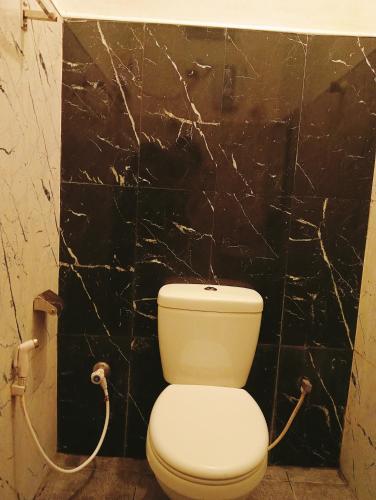 a toilet in a bathroom with a black marble wall at Eighty Seven Guest in Badulla