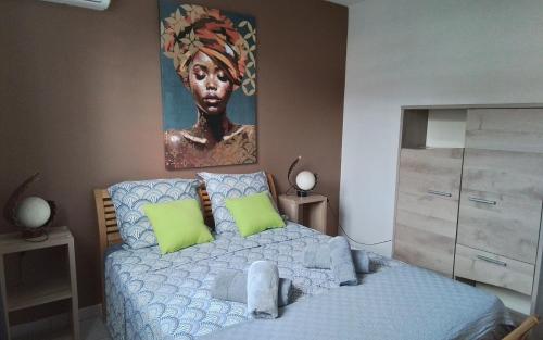 a bedroom with a bed with a portrait of a woman at Ti case Mellauman : Anse Plage in Les Trois-Îlets