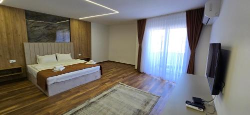 a bedroom with a bed and a flat screen tv at Hotel Pojata in Gjilan